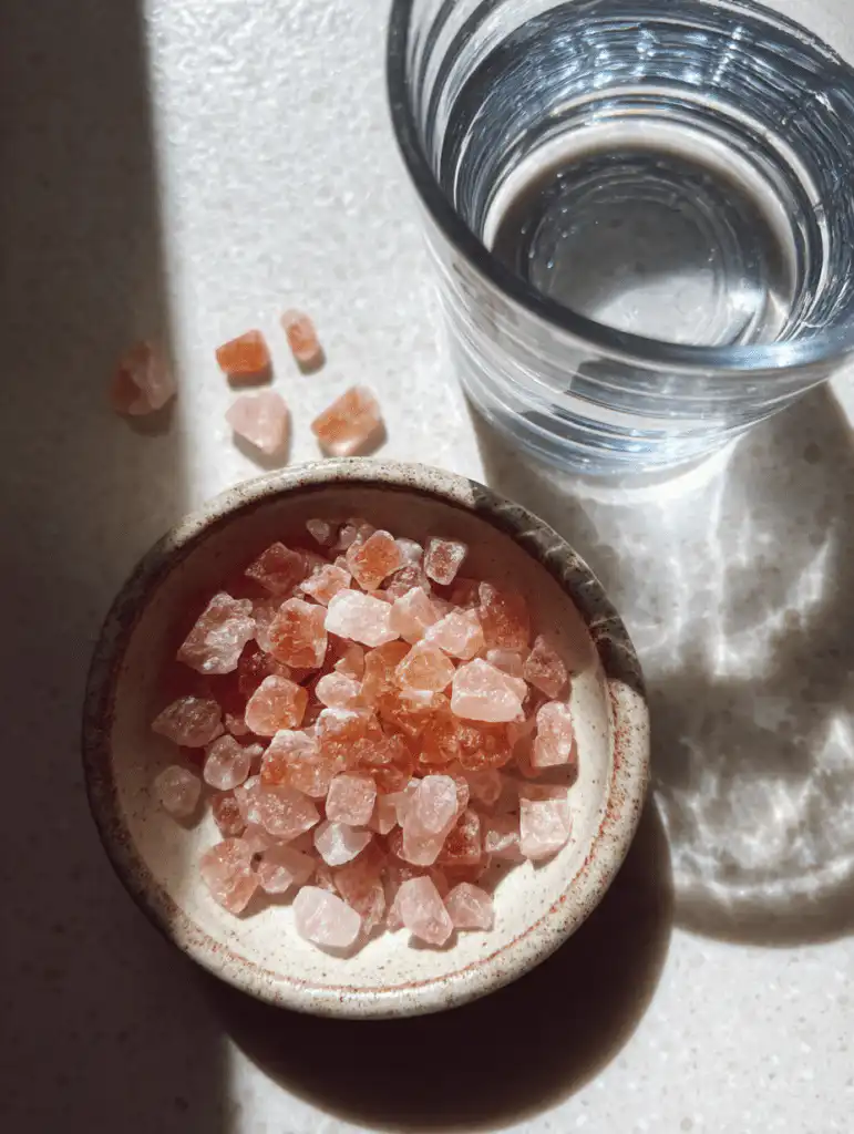 pink salt trick recipe ingredients in a glass with lemon and Himalayan salt