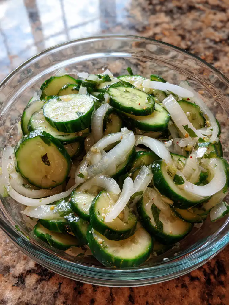 cucumber salad recipe mixing sliced cucumbers with dressing and onions